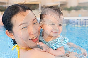 happy and beautiful Asian woman holding her little baby girl playful - Korean mother and adorable daughter playing on water at