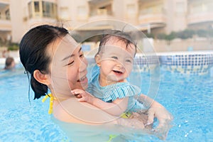 happy and beautiful Asian woman holding her little baby girl playful - Korean mother and adorable daughter playing on water at