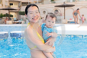 happy and beautiful Asian woman holding her little baby girl playful - Korean mother and adorable daughter playing on water at