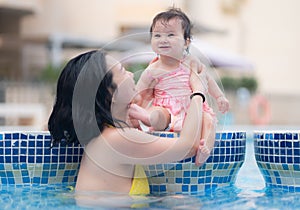 happy and beautiful Asian woman holding her little baby girl playful - Korean mother and adorable daughter playing on water at