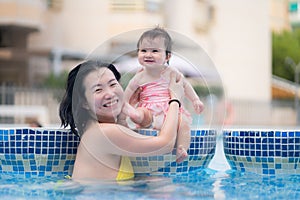 happy and beautiful Asian woman holding her little baby girl playful - Korean mother and adorable daughter playing on water at