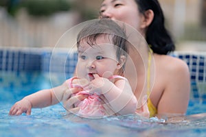 happy and beautiful Asian woman holding her little baby girl playful - Korean mother and adorable daughter playing on water at