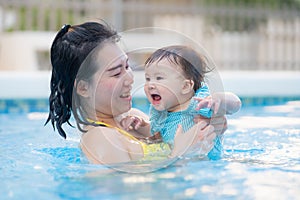 happy and beautiful Asian woman holding her little baby girl playful - Korean mother and adorable daughter playing on water at