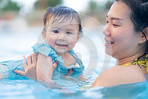 happy and beautiful Asian woman holding her little baby girl playful - Korean mother and adorable daughter playing on water at