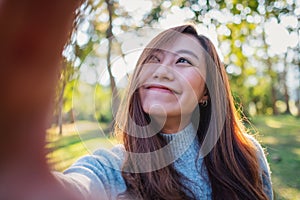 A happy beautiful asian woman making selfie photo in park