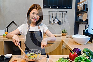 Happy beautiful asian woman prepare salad food in the kitchen.