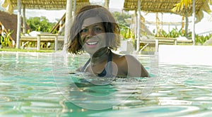 Happy and beautiful black African American woman in bikini having fun at tropical beach resort swimming pool relaxed and playful
