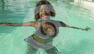 Happy and beautiful black African American woman in bikini having fun at tropical beach resort swimming pool relaxed and playful