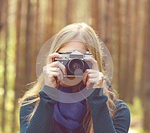 Happy, beautiful blond girl taking pictures in forest. Camp, tourism, hiking concept.