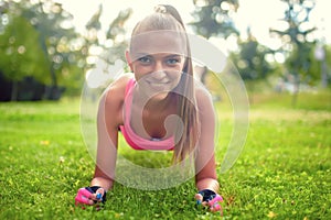 Happy, beautiful blonde girl doing abs and isometry on grass