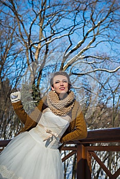 Happy beautiful bride in a snowy winter day. Sunny weather. stylish. with the wedding bouquet made from pine-tree hand made. mitte