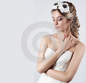 Happy beautiful bride woman blonde girl in a white wedding dress, with hair and bright make-up with veil in her eyes and flowers