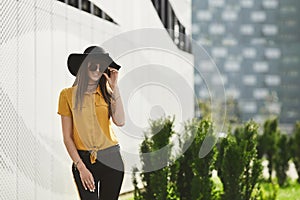 Happy and beautiful brunette model girl with perfect body in the yellow blouse and in the fashionable black hat