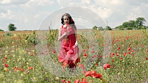 Happy beautiful brunette woman in red dress in a poppy field