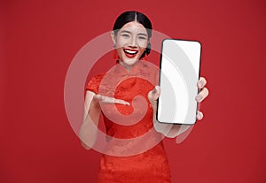 Happy Beautiful chinese Asian woman holding smartphone mockup and pointing finger blank screen and smiling isolated on red