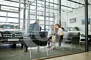 Happy beautiful couple is buying a new car at dealership. Family council