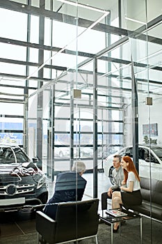 Happy beautiful couple is buying a new car at dealership. Family council