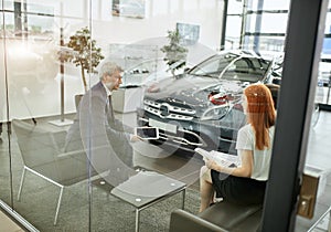 Happy beautiful couple is buying a new car at dealership. Family council