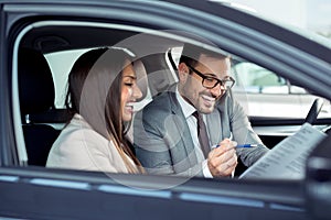 Happy beautiful couple is choosing a new car at dealership