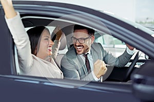 Happy beautiful couple is choosing a new car at dealership