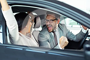 Happy beautiful couple is choosing a new car at dealership