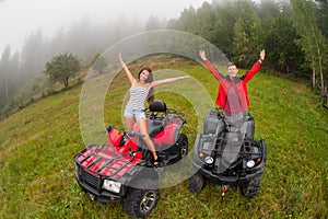 Happy beautiful couple sitting on four-wheelers ATV