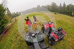 Happy beautiful couple standing near four-wheelers ATV