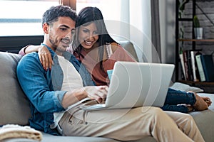 Happy beautiful couple using computer while sitting on the couch at home