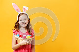 Happy beautiful cute little girl in easter bunny ears holds a basket with eggs. Spring close-up portrait of a child