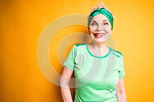 Happy beautiful elderly woman in sports bandage and t-shirt smiling getting ready for training
