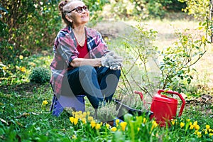 Happy beautiful senior woman 60 years old working in her garden planting flowers