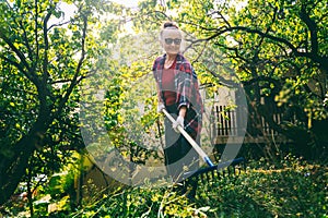 Happy beautiful senior woman 60 years old working in her garden using a rake. Garden care and an active lifestyle for retirees