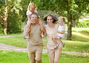 Happy beautiful family of four running in park