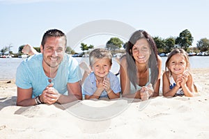 Happy beautiful family with kids lying together on european atlantic beach during summer vacation