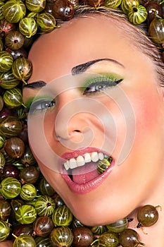 Happy beautiful female face in the gooseberry