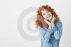 Happy beautiful girl with curly red hair smiling looking at camera over white background. Copy space.