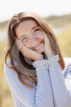 Happy beautiful girl holding her cheeks with a laugh, looking at the camera. Pretty young woman clean fresh skin