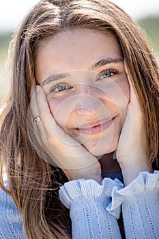 Happy beautiful girl holding her cheeks with a laugh, looking at the camera. Pretty young woman clean fresh skin