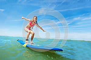 Happy beautiful girl learn to surf on surfboard