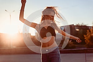 happy beautiful girl in lingerie and jeans dancing in the city at sunset