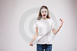 Happy and beautiful girl measuring her waist fitness with a ruler over grey background. Health concept