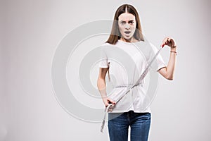 Happy and beautiful girl measuring her waist fitness with a ruler over grey background. Health concept