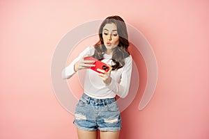 Happy beautiful girl playing mobile video game, holding smartphone horizontally, watching on cellphone with excited face