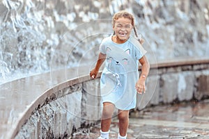 Happy beautiful girl running through the spray of water