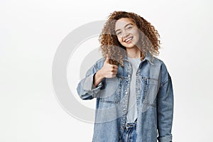 Happy beautiful girl showing thumbs up, like and approve, recommending smth good, praising or complimenting, standing