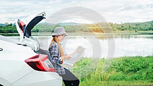 Happy beautiful girl traveling in a hatchback car with map