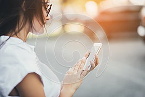 Happy beautiful girl using smart phone in the city, summer girl portrait. Close up. Sunshine background