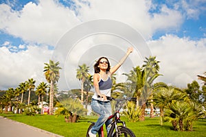 Happy beautiful girl woman riding bicycle with raised hands