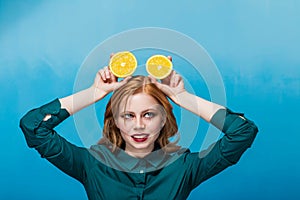 Happy beautiful joyful red-haired girl with makeup in a green blouse on a blue background