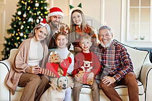 Happy beautiful large family with dog labrador retriever sitting on couch near decorated xmas tree